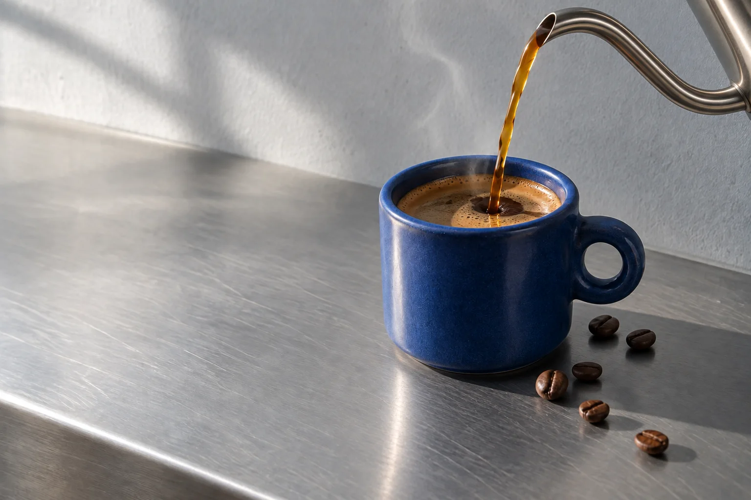 A slender stream of coffee pours into the cobalt cup.